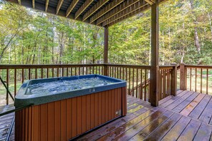 Un bain à remous sur une terrasse en bois, avec vue sur une forêt.
