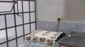 Una cocina compacta con horno integrado, una ventana con celosía metálica y suelo de baldosas.
