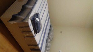 Una caja de cartón con un objeto negro en su interior, posiblemente un paquete o artículo, sobre una superficie de madera.