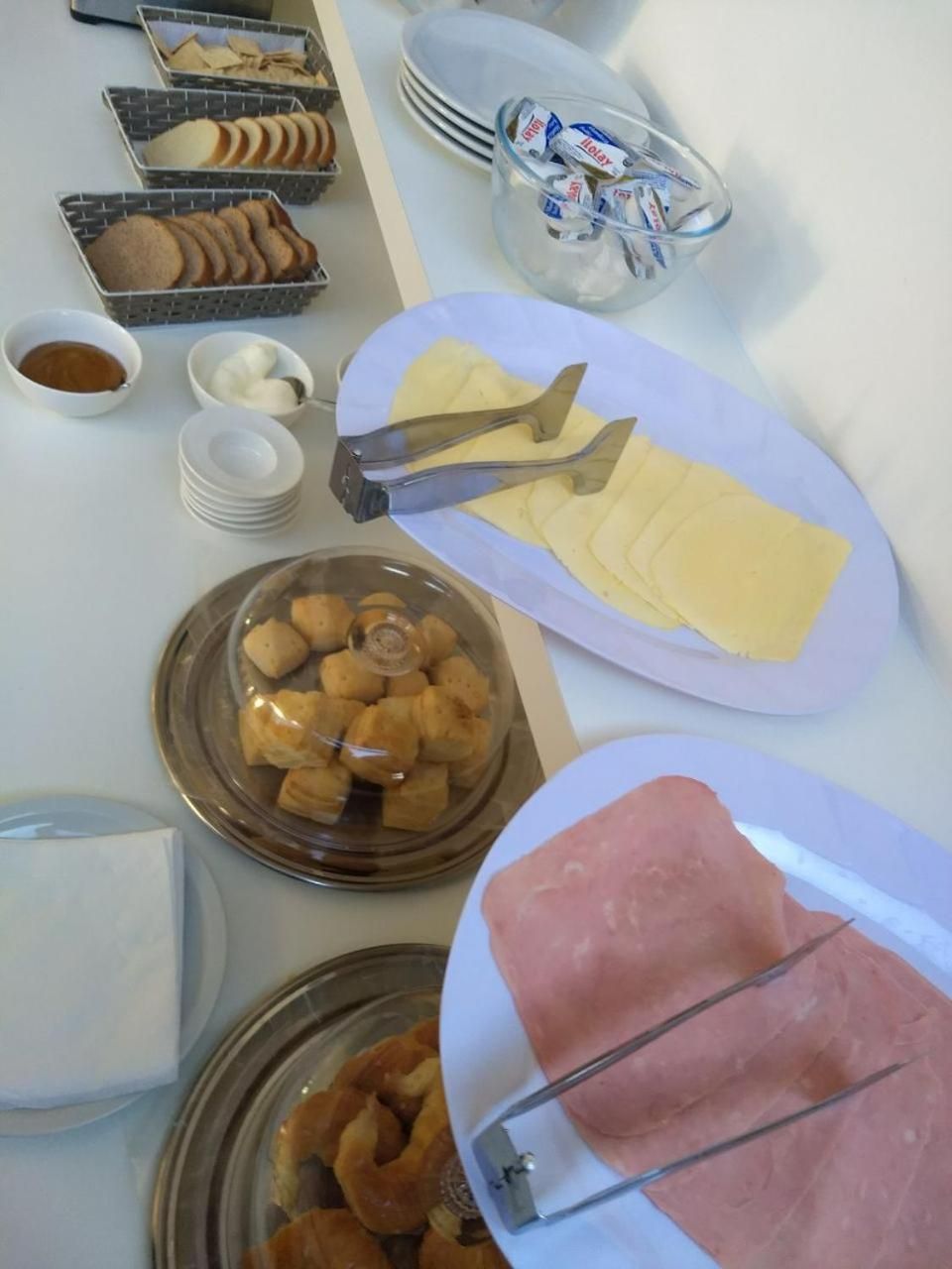 Une table de buffet proposant divers aliments, notamment du pain, des pâtisseries et de la viande.