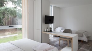 A modern hotel room with a bed, a desk, a chair, and a TV. - Ciudad Prado Hotel (Córdoba)