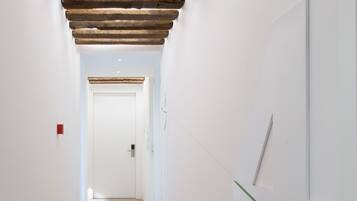 Un pasillo con techo de madera, paredes blancas y suelo de baldosas.