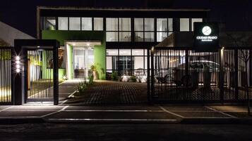 A modern building with a green facade, large windows, and a gated entrance.