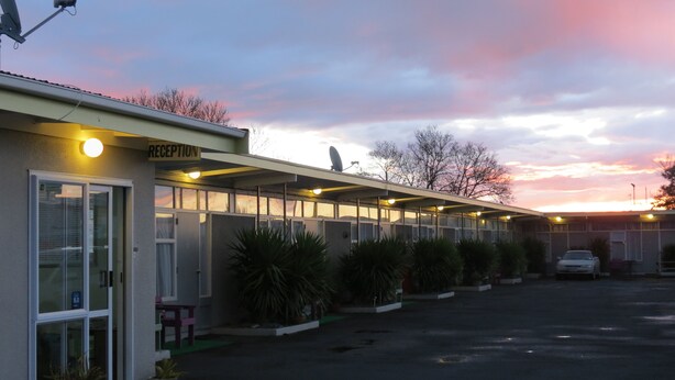 Motel amb zona de recepció, habitacions individuals i pàrquing.