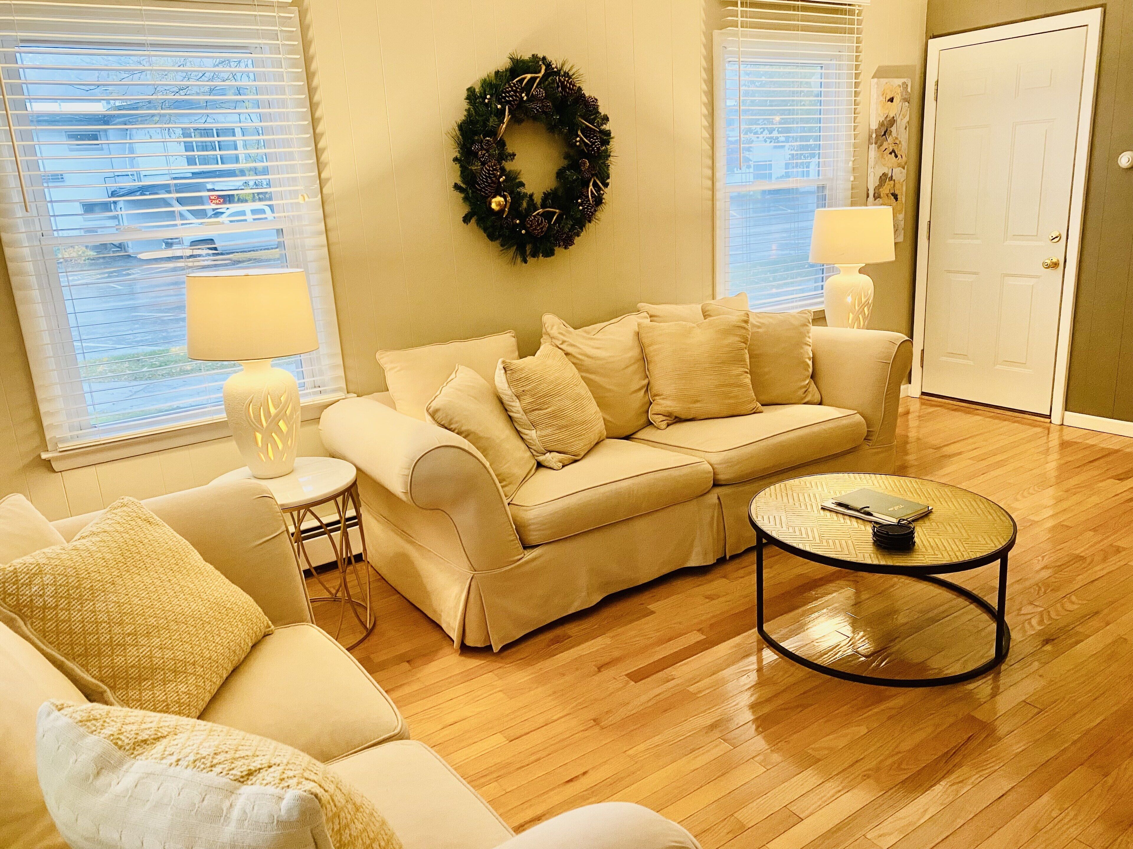 A living room with a beige sofa, a round coffee table, and a small side table with a lamp.
