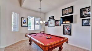 A pool table in a room with a ceiling fan, framed sports memorabilia on the walls, and a window with blinds. - 6 Minutes from Airport, 8 Minutes to Strip,  Sleeps 14  6 Bedroom, 4 Bath (Las Vegas)