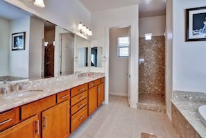 Bathroom features a double sink, shower, and large mirror.