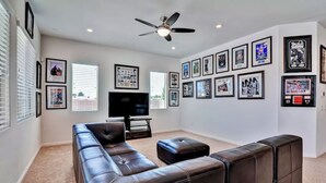 A living room with a large sectional sofa, a television, and a ceiling fan. The walls are decorated with framed pictures. - 6 Minutes from Airport, 8 Minutes to Strip,  Sleeps 14  6 Bedroom, 4 Bath (Las Vegas)