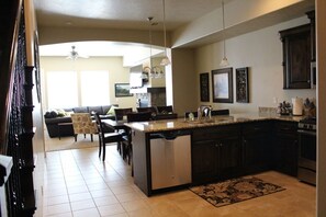 Enjoy cooking in the well-equipped kitchen with a central island, dishwasher, and sink, adjacent to a dining area with a sofa and chairs.