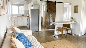 Una cucina moderna con frigorifero, piano cottura e lavello. È presente una zona pranzo con tavolo e sedie.