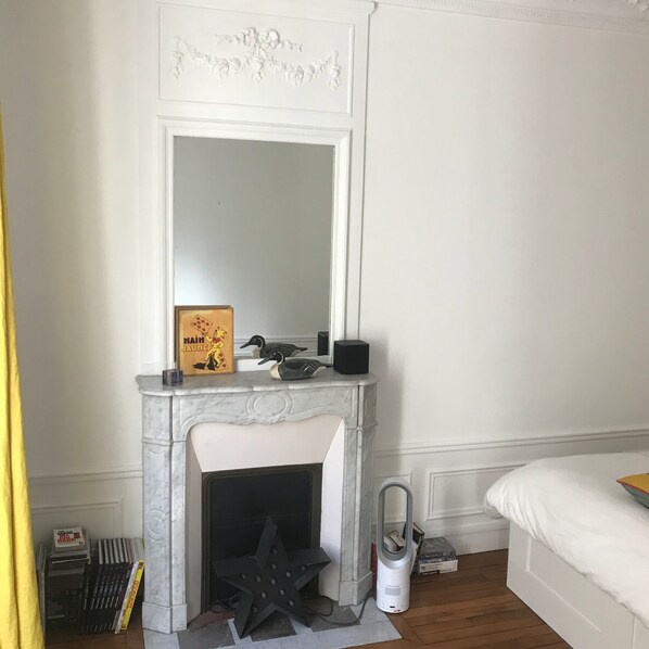 A room with a white fireplace, a mirror above it, and a bed to the right. - Large family 3 rooms apartment (60m2), next to metro Convention (Paris)
