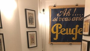 Un couloir étroit avec un banc, des tableaux encadrés accrochés aux murs et un panneau avec du texte.