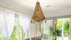 Un comedor con una mesa de madera, sillas de mimbre y una lámpara colgante.