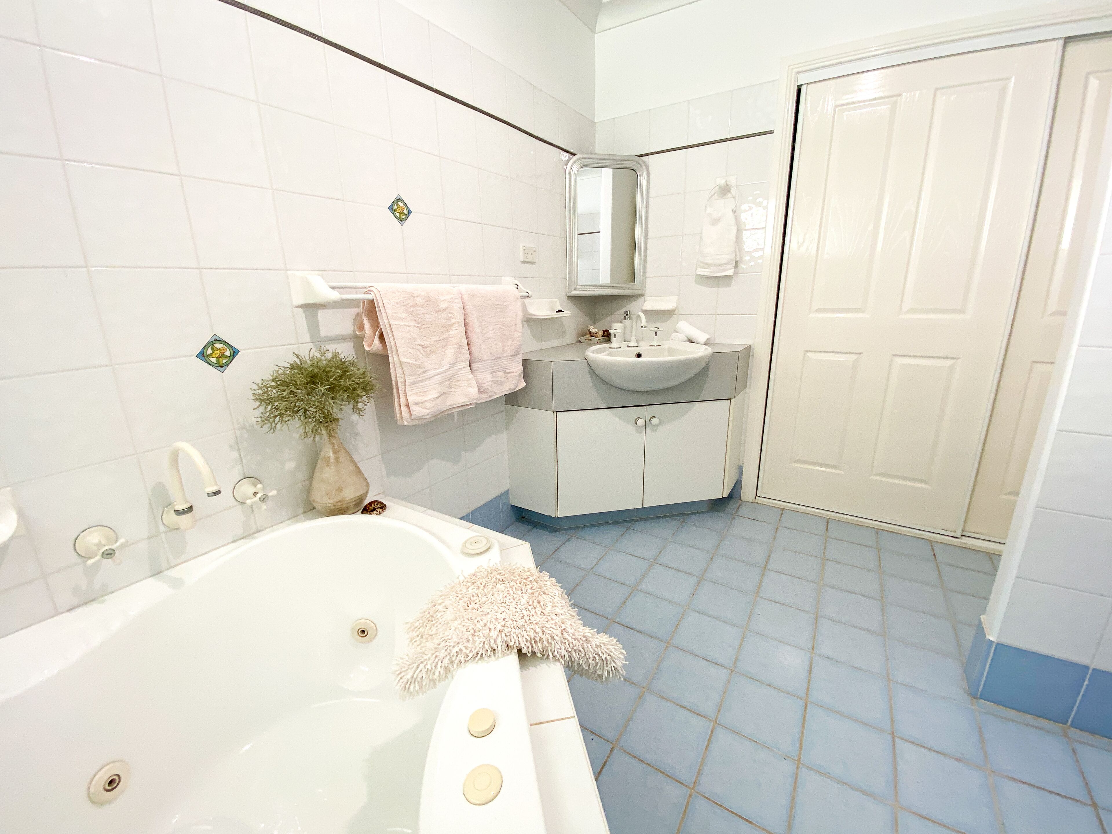 A bathroom with a bathtub, a sink, a mirror, and a door.