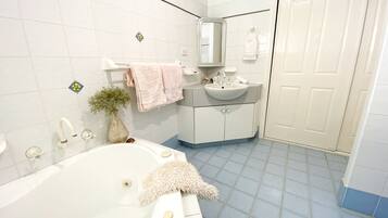 A bathroom with a bathtub, a sink, a mirror, and a door.