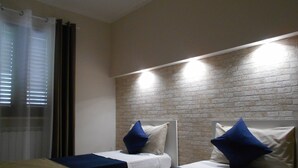 Une chambre d’hôtel avec deux lits, chacun doté d’une tête de lit bleue et blanche, et un mur en briques.