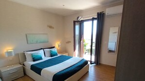 Une chambre à coucher avec un lit, des tables de chevet, un tableau et une vue sur l’extérieur, visible à travers une porte coulissante.