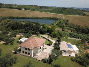 A house with a tiled roof, a solar panel, and a pond in the background.