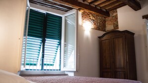 Une chambre Ă coucher avec un lit, une armoire en bois et une fenĂŞtre avec des volets.