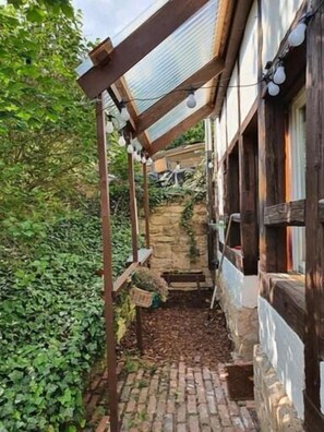 A narrow outdoor corridor with a wooden structure, stone wall, and greenery. - Hotel Bad Langensalza Eichenhof (Bad Langensalza)