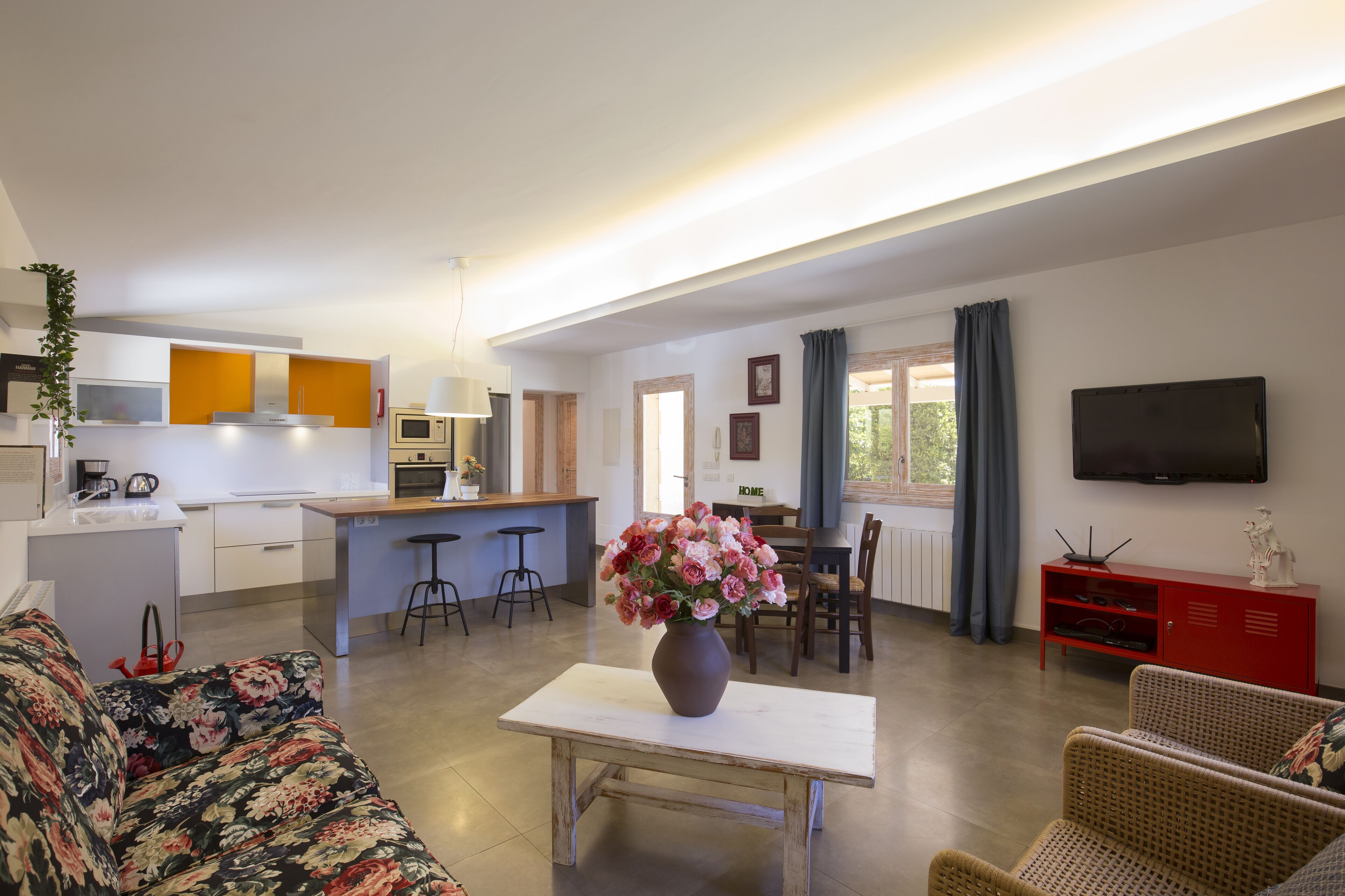 A modern living room with a sofa, a dining table, and a kitchen area in the background.