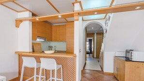 A compact kitchen with wooden cabinets, a bar area with two white chairs, and a microwave on the counter. - Adeje paradise Duplex with sea view (adeje)