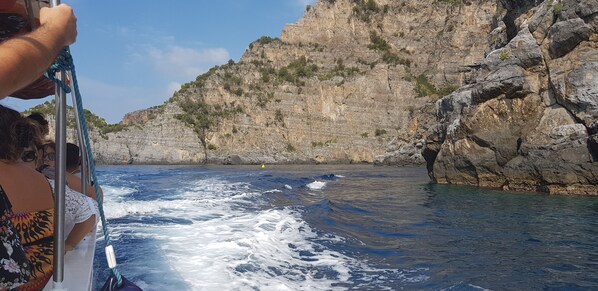 A boat navigating through a rocky coastal area with cliffs in the background.