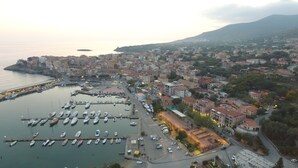 An aerial view of a coastal town with a marina, buildings, and a mountain in the background. - Cozy Green Kitchen Apartment (marina di camerota)