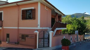A two-story building with a balcony, a gated entrance, and a staircase leading to the upper floor. - Cozy Green Kitchen Apartment (marina di camerota)