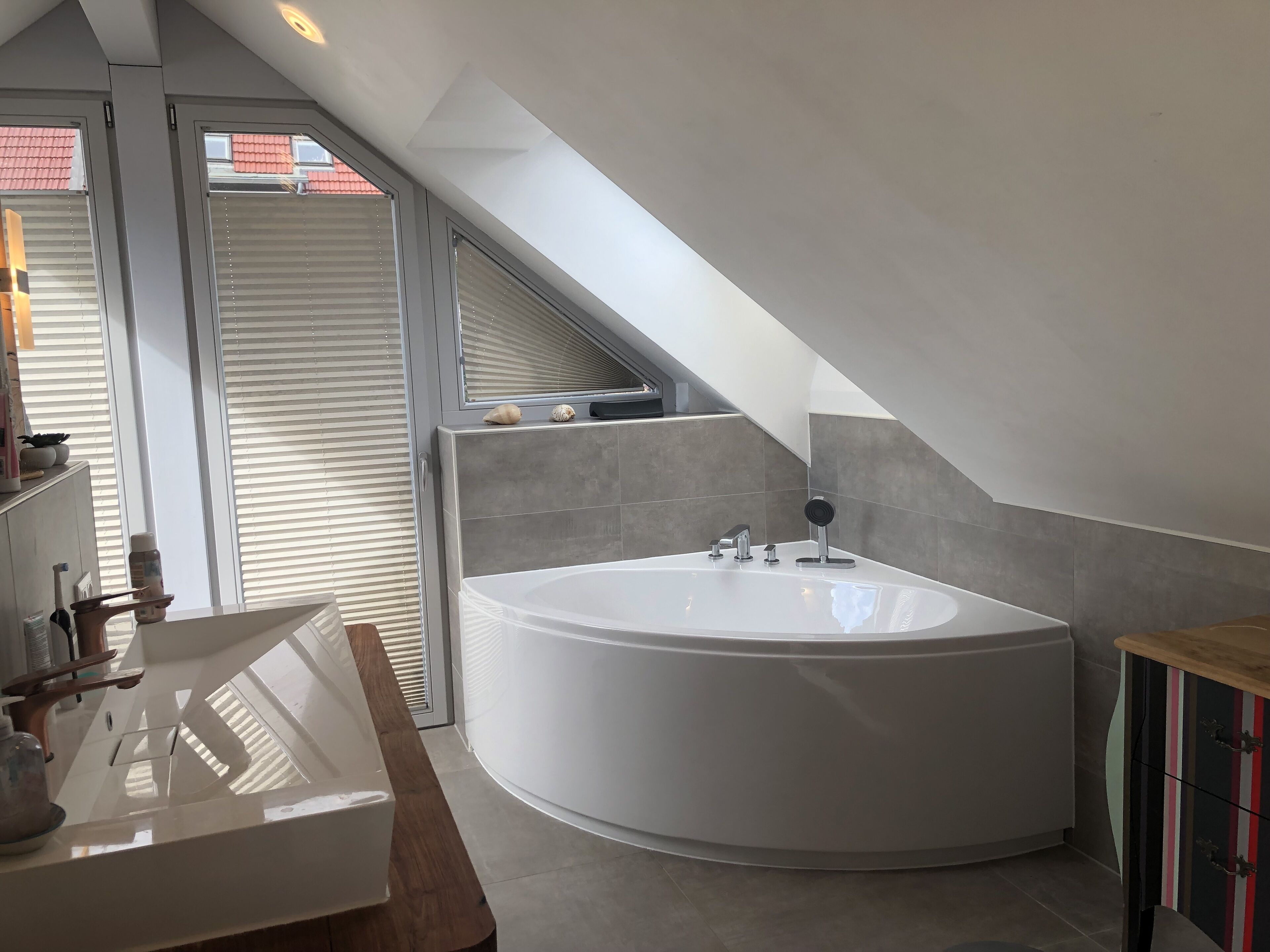 Une salle de bain moderne avec une baignoire sur pieds, un meuble-lavabo avec un miroir et une fenêtre avec des stores.