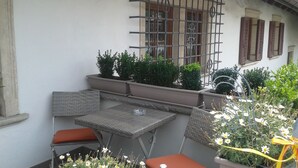 A small outdoor seating area with a table and two chairs, surrounded by potted plants and flowers. - Apartment in the center of St. Pauls - Appiano - near Caldaro and Bolzano (Pauls)