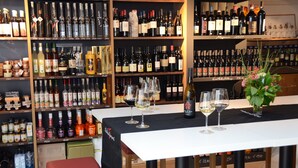 A wine tasting room with shelves of wine bottles and glasses on a table. - Apartment in the center of St. Pauls - Appiano - near Caldaro and Bolzano (Pauls)