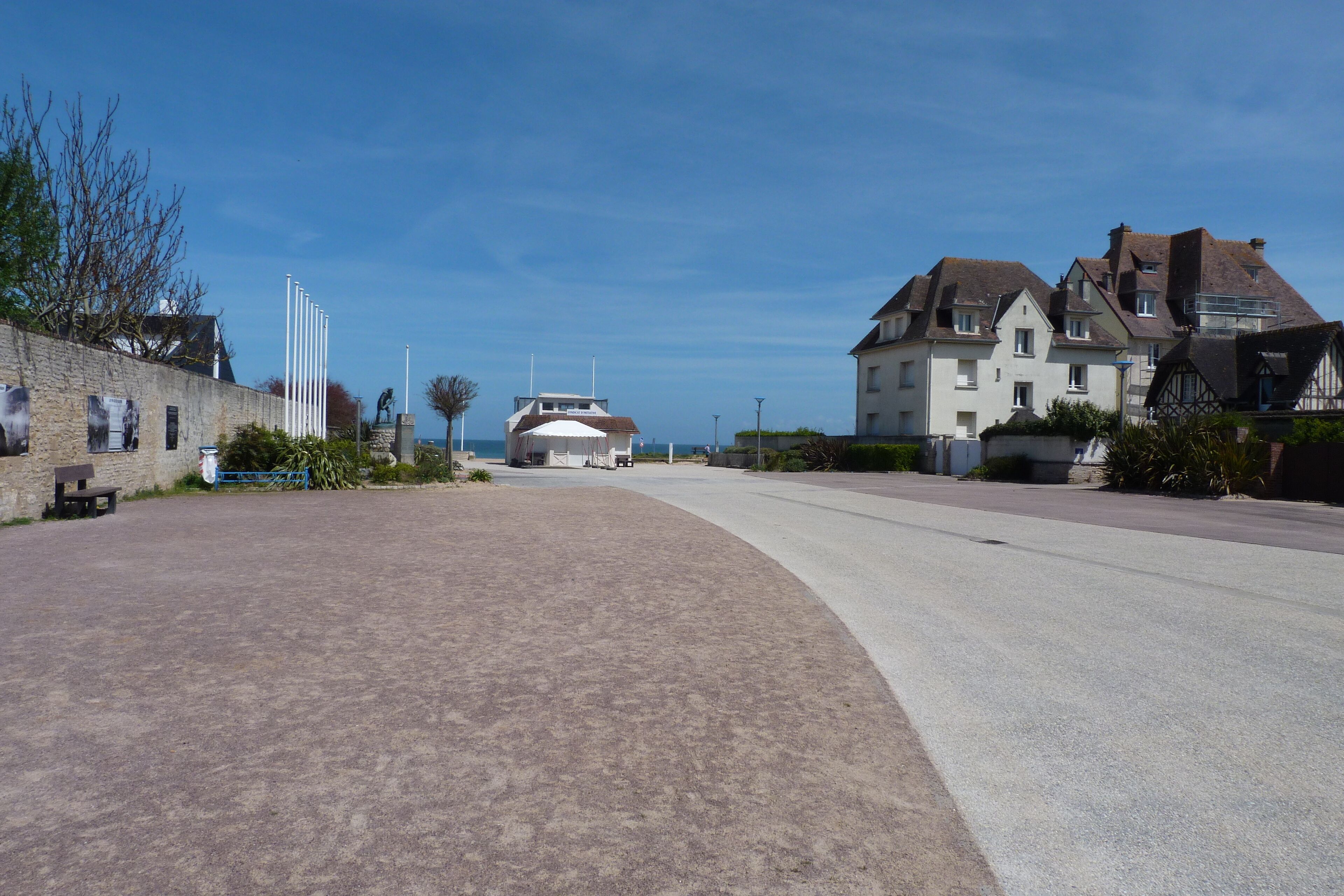 Une rue pavée, bordée d’un côté par un mur de pierres et de l’autre par une rangée de maisons.