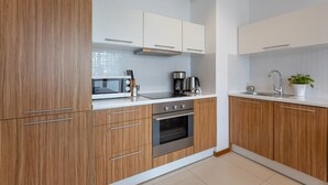 A modern kitchen with wooden cabinets, a stainless steel oven, a microwave, and a coffee maker.