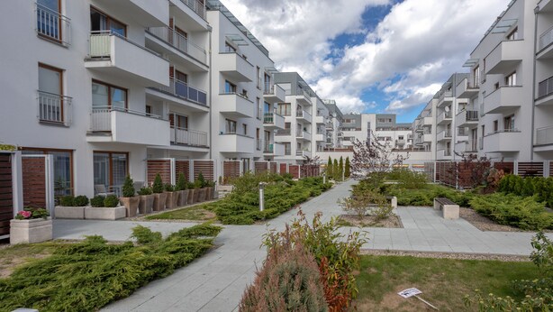 A modern apartment complex with multiple balconies, a central pathway, and landscaped areas.