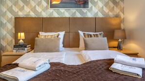 A hotel room with a large bed, two nightstands, a lamp, and a painting of a sunset over the ocean.