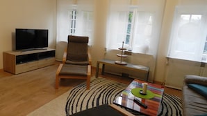 Un salon comprenant un téléviseur, un canapé, un fauteuil, une table basse et un tapis.