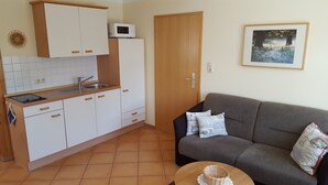 A compact living space with a kitchenette, a sofa, and a framed picture on the wall.