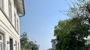 A cobblestone street lined with trees and a building with a balcony.
