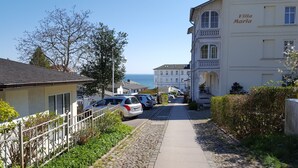 A coastal street with parked cars, a white building labeled "Villa Maria," and a clear view of the sea.