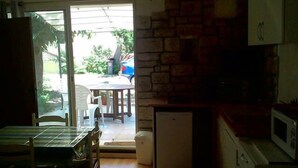 Cozinha com geladeira, micro-ondas e área de jantar com mesa e cadeiras.