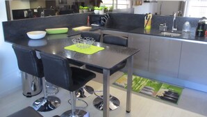 Una cocina moderna con comedor, que incluye una mesa negra, sillas y un lavamanos de acero inoxidable.