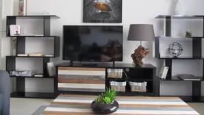 Una sala de estar moderna con un televisor de pantalla plana, estanterías negras y un tapete a rayas.