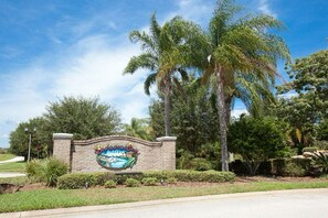 A sign for a resort with a beach theme, surrounded by palm trees and greenery.