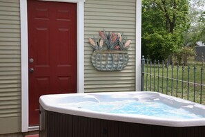 Une porte rouge, un pot de fleurs décoratif et un jacuzzi devant une maison.