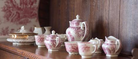 A wooden cabinet with a tea set including cups, saucers, a teapot, and a sugar bowl.