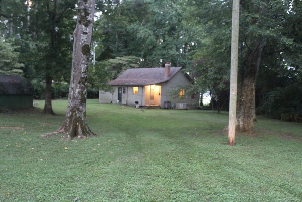 A house with a sloped roof and a chimney, surrounded by a grassy yard and trees. - The Bird's Nest on the Tennessee river (Rogersville)
