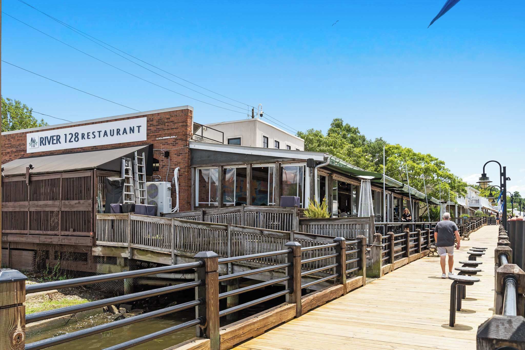 A riverside restaurant with a wooden deck and a sign reading 'River 128 Restaurant.'