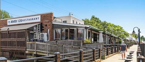 A riverside restaurant with a wooden deck and a sign reading 'River 128 Restaurant.'