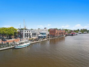 Een stad aan de rivier met een historisch gebouw, een dok met een zeilboot en een brug.